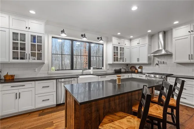 a kitchen with stainless steel appliances granite countertop a stove a sink dishwasher a microwave oven with white cabinets and wooden floor