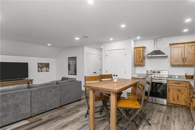 a kitchen with stainless steel appliances granite countertop a stove a sink dishwasher and a refrigerator with wooden floor