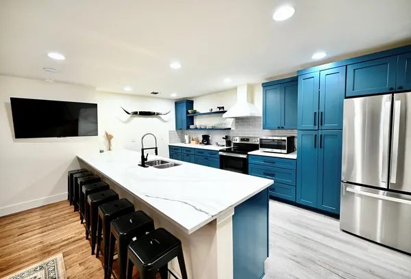 a kitchen with granite countertop a refrigerator stove a sink dishwasher and microwave with wooden floor