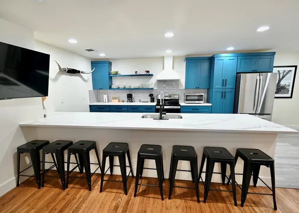 a kitchen with stainless steel appliances granite countertop a dining table chairs refrigerator and sink