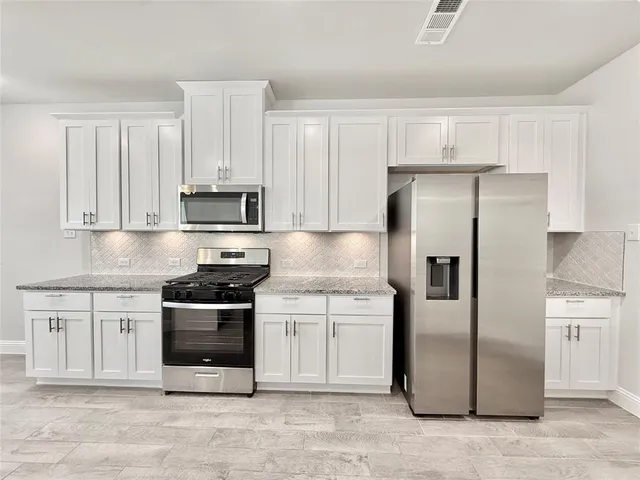 a kitchen with stainless steel appliances granite countertop a refrigerator stove and white cabinets