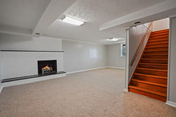 an empty room with a fireplace and stairs