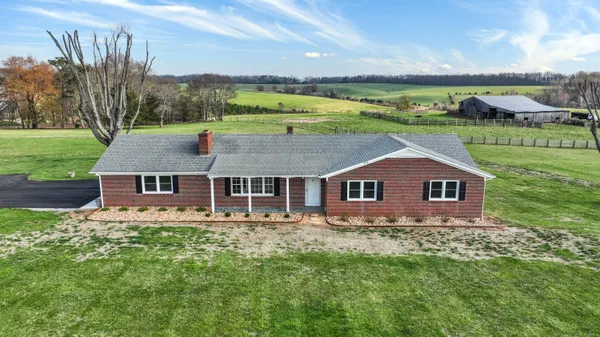 a view of a big house with a big yard and large trees