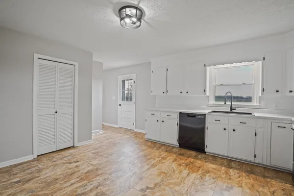 a large white kitchen with granite countertop a stove a sink dishwasher and a refrigerator