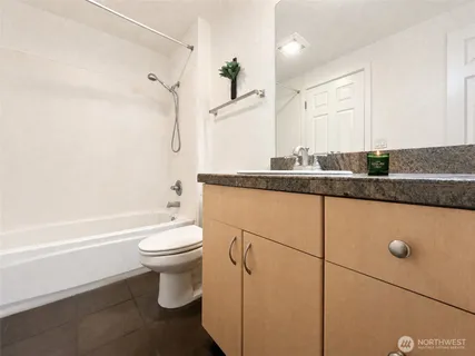 a bathroom with a granite countertop sink a toilet a mirror and bathtub