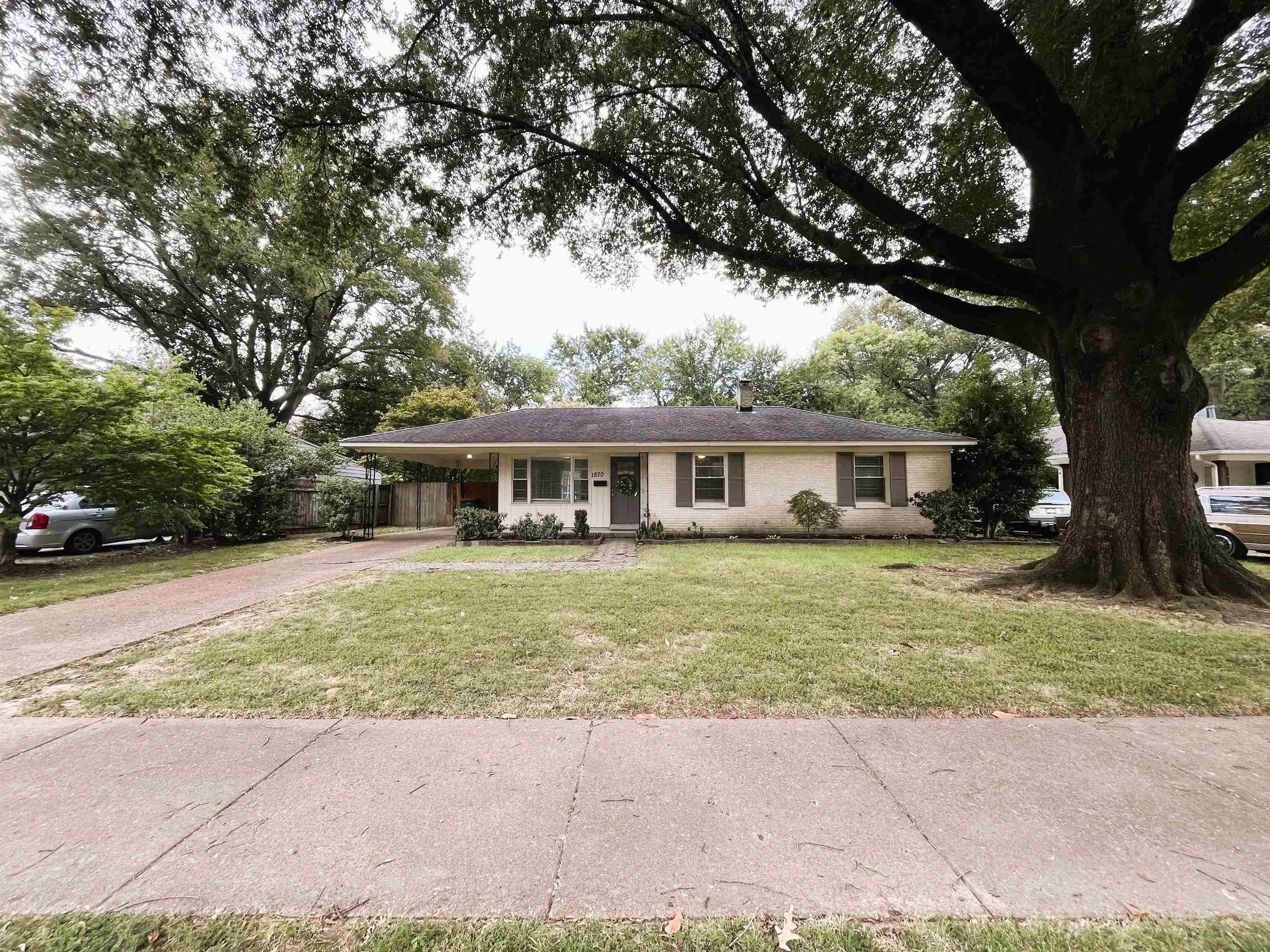 Single story home with asphalt driveway, an attached carport, a chimney, and brick siding