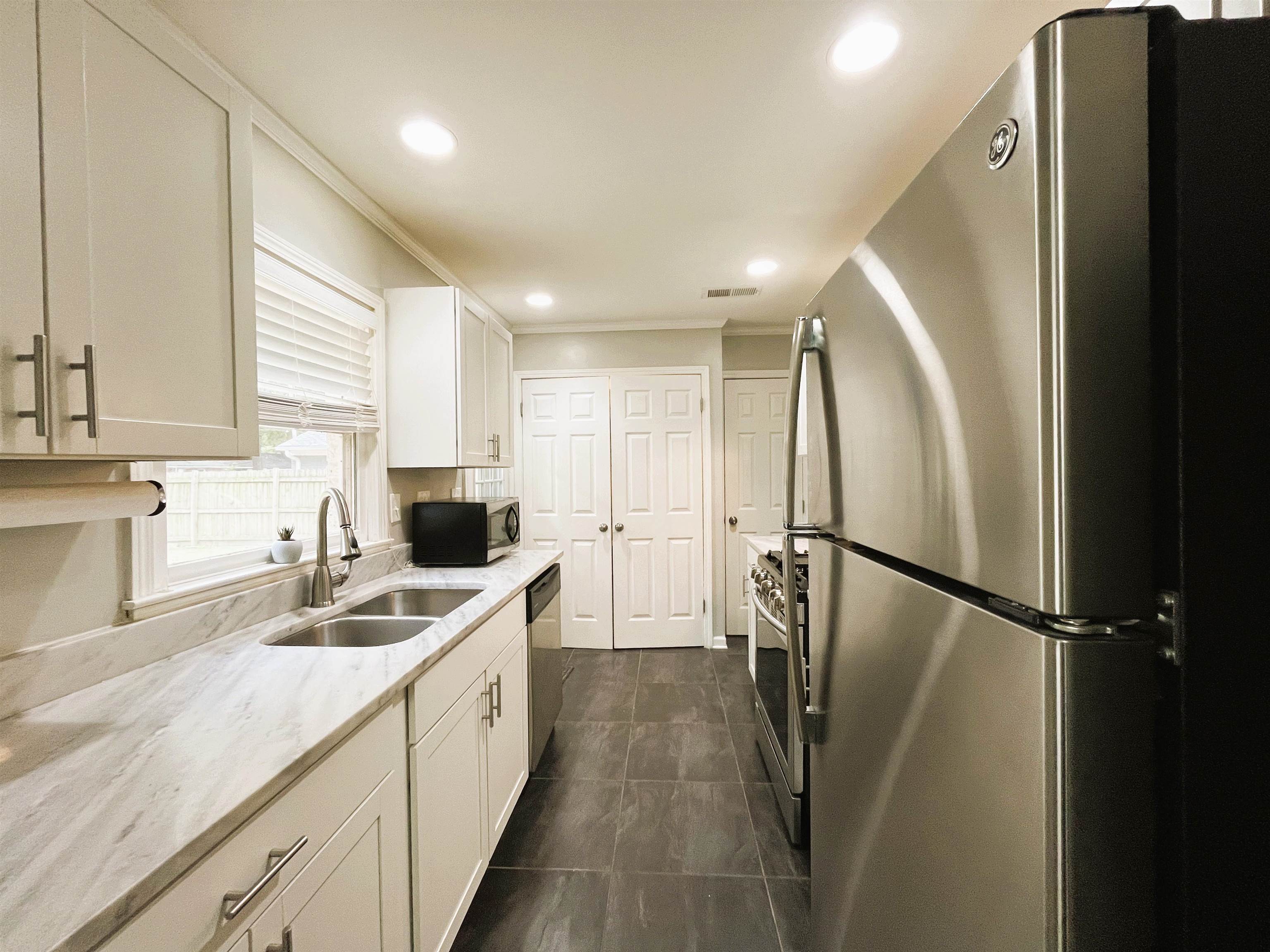 1570 Dearing Road Memphis, TN 38117 - Photo 6 of 16 Kitchen with appliances with stainless steel finishes, recessed lighting, light stone counters, white cabinetry, and crown molding