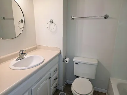 a bathroom with a toilet sink vanity granite and shower