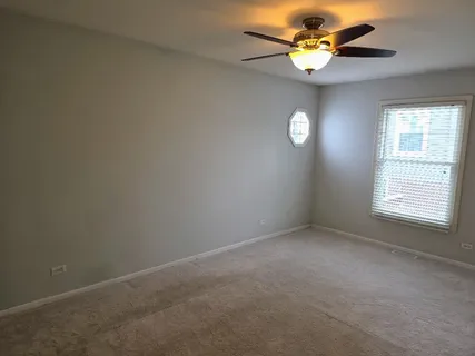 an empty room with a window and a fan