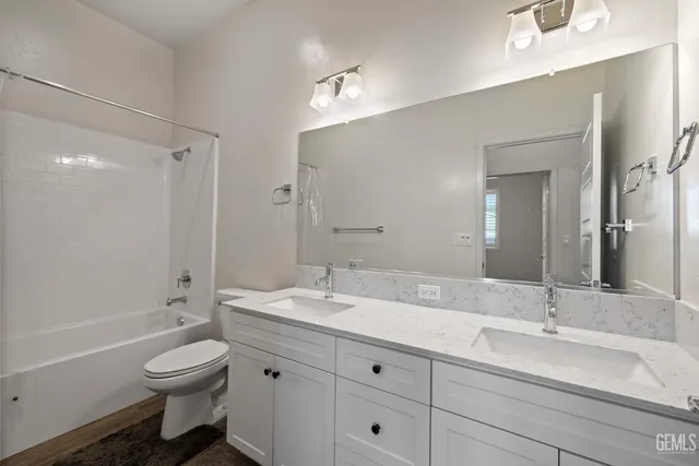 a bathroom with a double vanity sink toilet mirror and bathtub