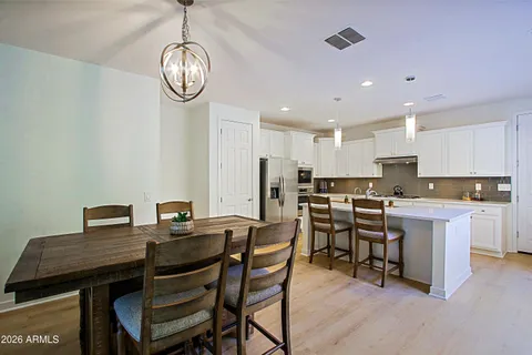 a kitchen with stainless steel appliances a sink a stove a refrigerator cabinets and chairs