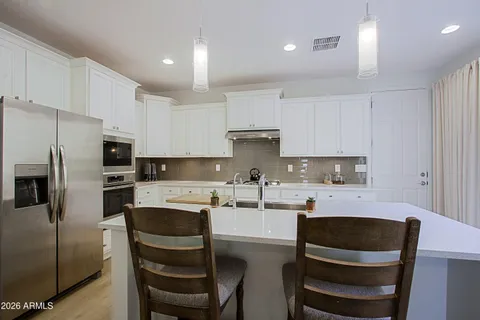 a kitchen with kitchen island stainless steel appliances a stove a sink a refrigerator a center island and a stove