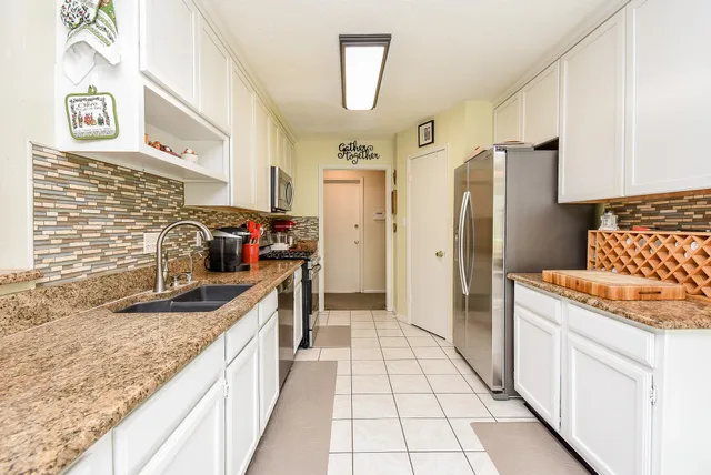 a living room with chairs and kitchen view