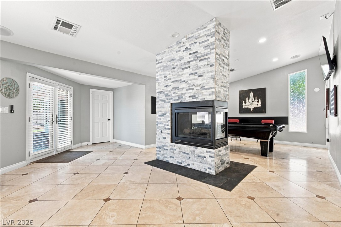 7744 Rancho Destino Road Las Vegas, NV 89123 - Photo 35 of 48 A striking dual-sided stone fireplace anchors this open layout finished with tile flooring.