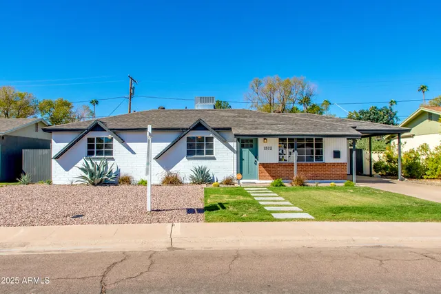 a front view of a house with a yard and potted plants