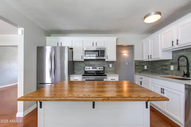 a kitchen with kitchen island a counter top space cabinets and stainless steel appliances