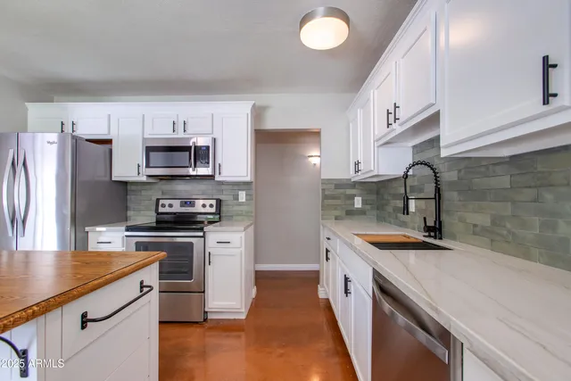 a kitchen with stainless steel appliances a sink stove refrigerator and cabinets