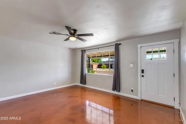 an empty room with window and ceiling fan