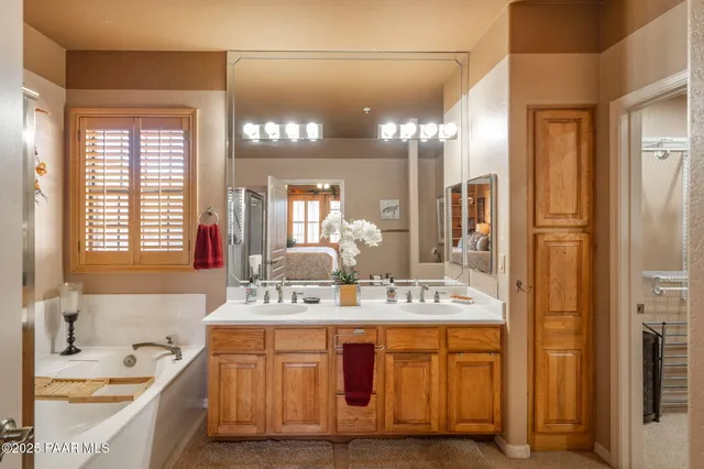 a bathroom with a sink double vanity granite tub shower and a mirror