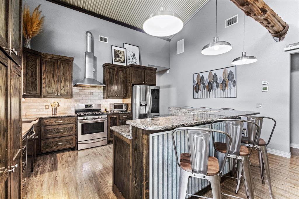 595 Pleasant Home Road Sherman, TX 75092 - Photo 10 of 40 a kitchen with stainless steel appliances granite countertop a stove top oven a sink a dining table and chairs with wooden floor