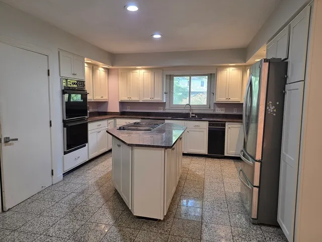 a kitchen with stainless steel appliances granite countertop a stove a sink and a refrigerator