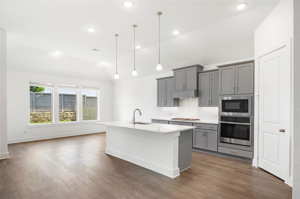2900 Barbary Road McKinney, TX 75071 - Photo 13 of 36 Bright kitchen and living area featuring wood-finish flooring, recessed lighting, and a vaulted ceiling