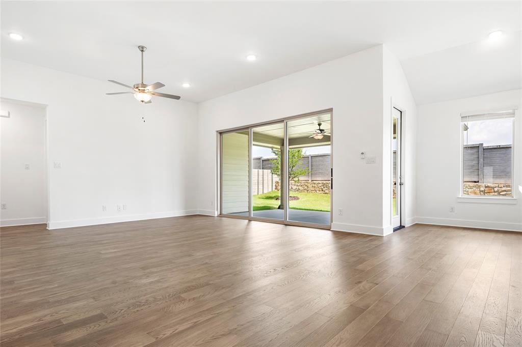 2900 Barbary Road McKinney, TX 75071 - Photo 18 of 36 Spacious interior featuring wood-finish flooring, ample recessed lighting, a ceiling fan, and large sliding glass doors opening to a covered patio and fenced backyard with a stone retaining wall
