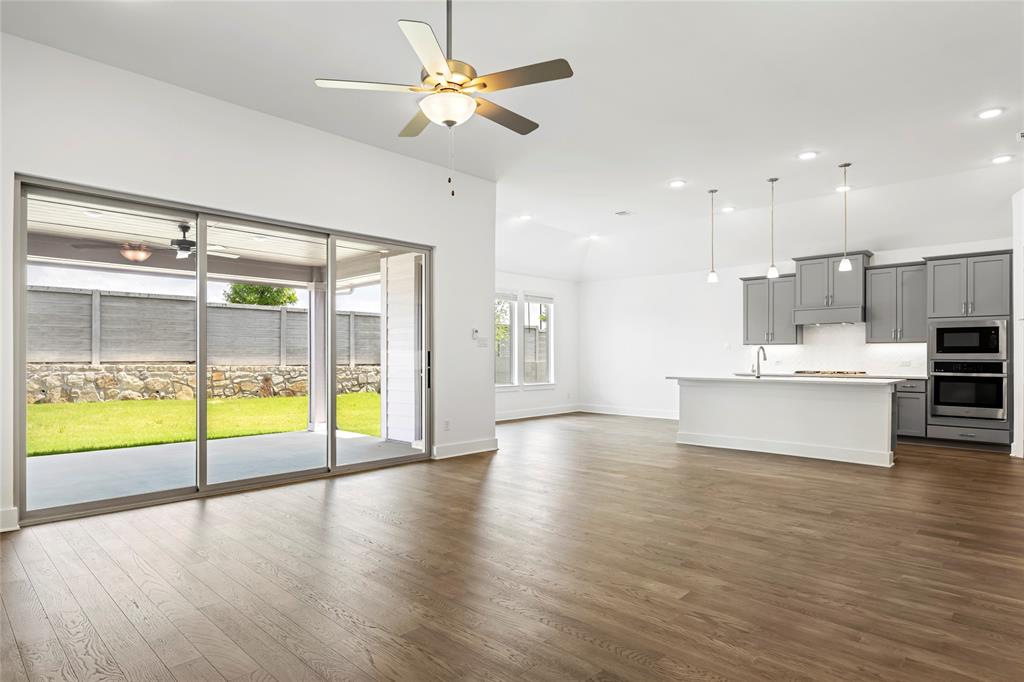 2900 Barbary Road McKinney, TX 75071 - Photo 19 of 36 Spacious open-concept interior featuring wood-finish flooring, a contemporary ceiling fan, and large sliding glass doors opening to a covered patio