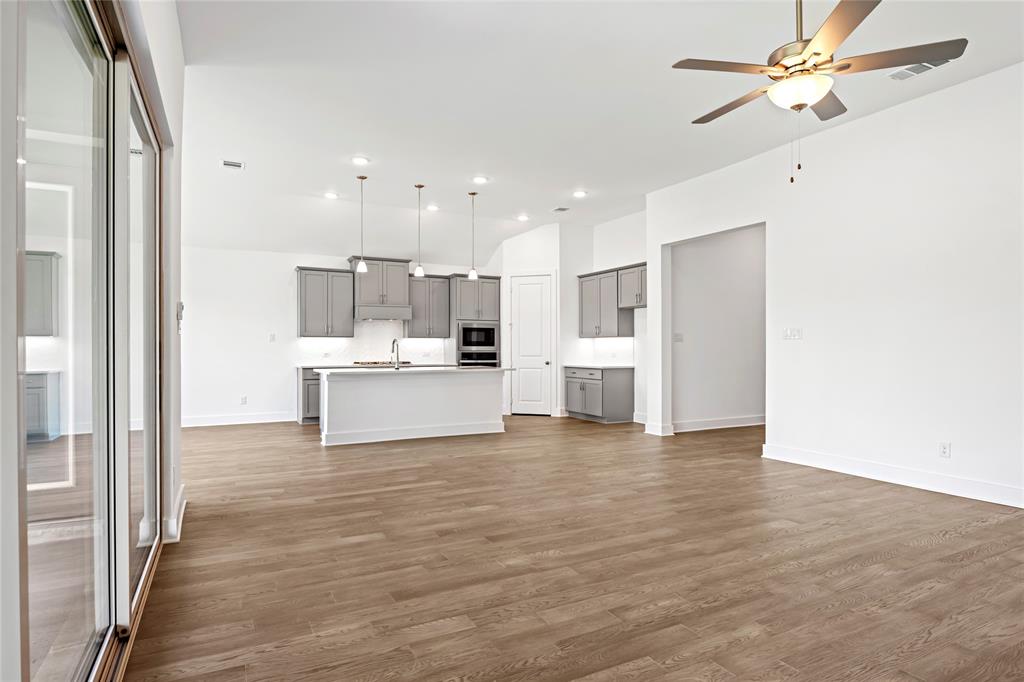 2900 Barbary Road McKinney, TX 75071 - Photo 20 of 36 Open-concept kitchen and living area featuring wood-finish flooring, a kitchen island with sink, gray cabinetry, built-in stainless steel appliances, and a ceiling fan