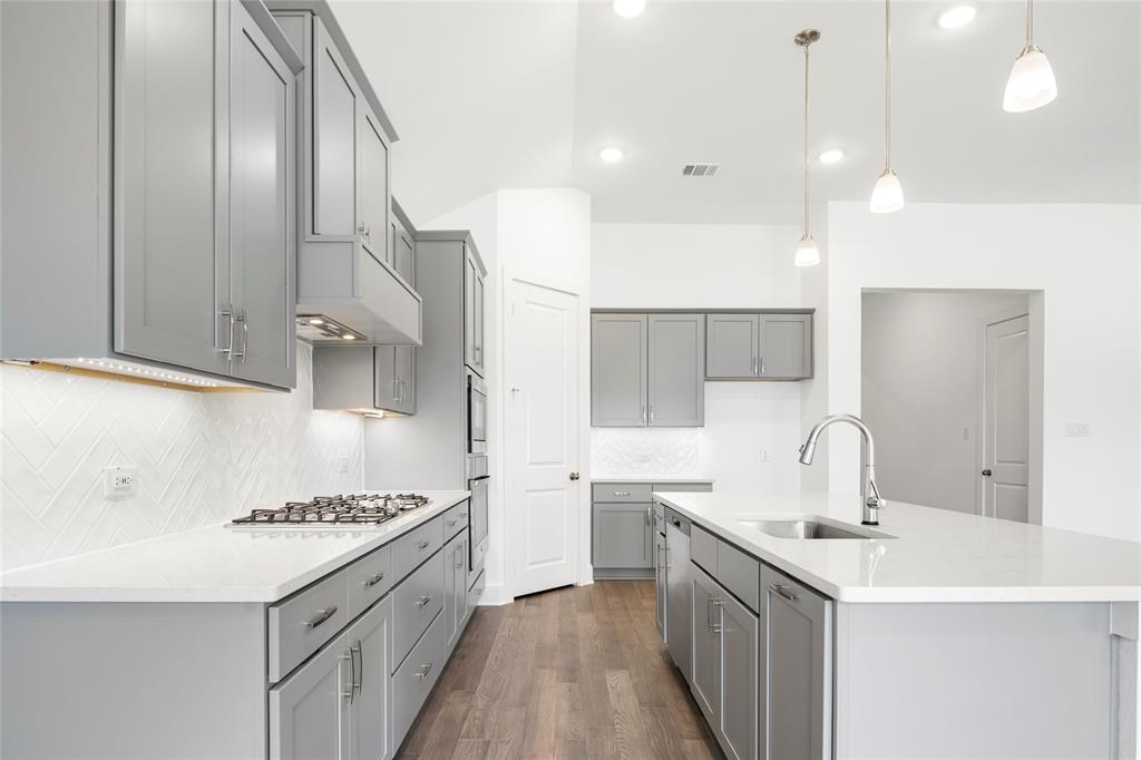 2900 Barbary Road McKinney, TX 75071 - Photo 7 of 36 Kitchen featuring an island with an undermount sink, pendant lighting, shaker-style cabinetry, white countertops, and wood-finish flooring
