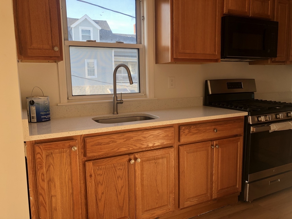 83-85 Neptune Street, Unit 2 Lynn, MA 01905 - Photo 2 of 8 a kitchen with stainless steel appliances a stove microwave and cabinets