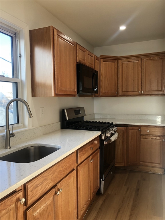 83-85 Neptune Street, Unit 2 Lynn, MA 01905 - Photo 3 of 8 a kitchen with stainless steel appliances granite countertop a sink stove and cabinets