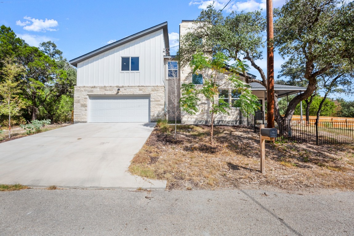 18208 Gregg Bluff Road Jonestown, TX 78645 - Photo 5 of 28 View of front facade featuring board and batten siding, stone siding, an attached garage, and driveway