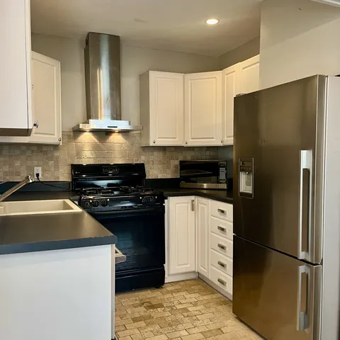 a kitchen with a refrigerator stove and white cabinets
