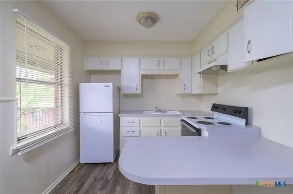 a kitchen with kitchen island white cabinets and refrigerator