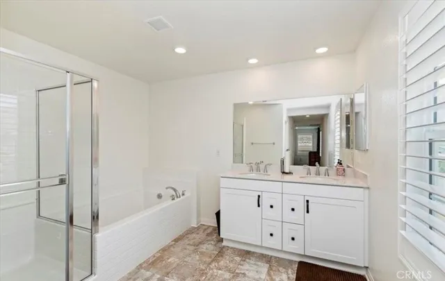 a bathroom with a double vanity sink mirror and bathtub