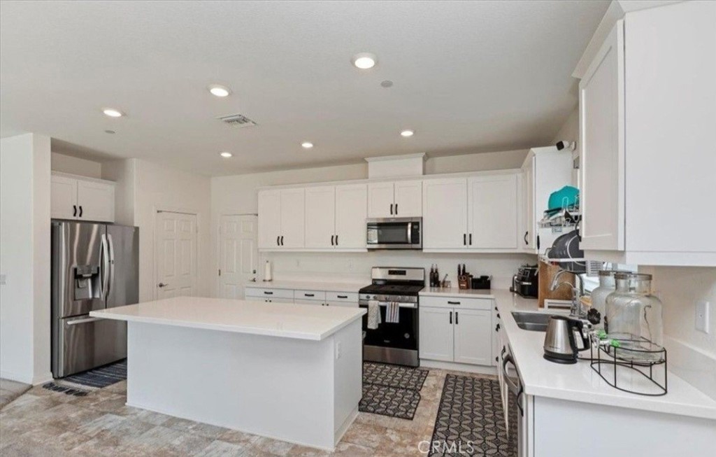 21288 Telegraph Road Riverside, CA 92507 - Photo 7 of 23 a kitchen with stainless steel appliances white cabinets a sink a stove a refrigerator and a center island