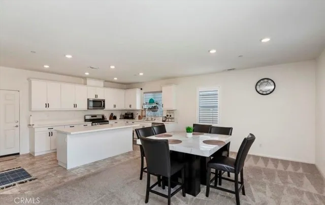a kitchen with a dining table chairs and white stainless steel appliances