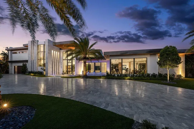 a view of a brick house with a yard potted plants and a large tree