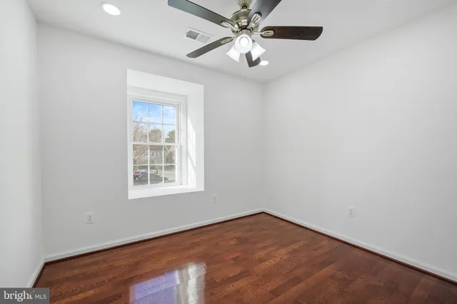 an empty room with a window and a fan