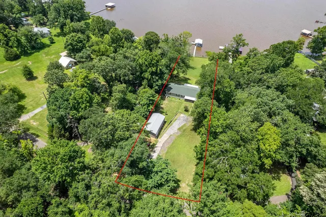 an aerial view of residential house with outdoor space and trees all around