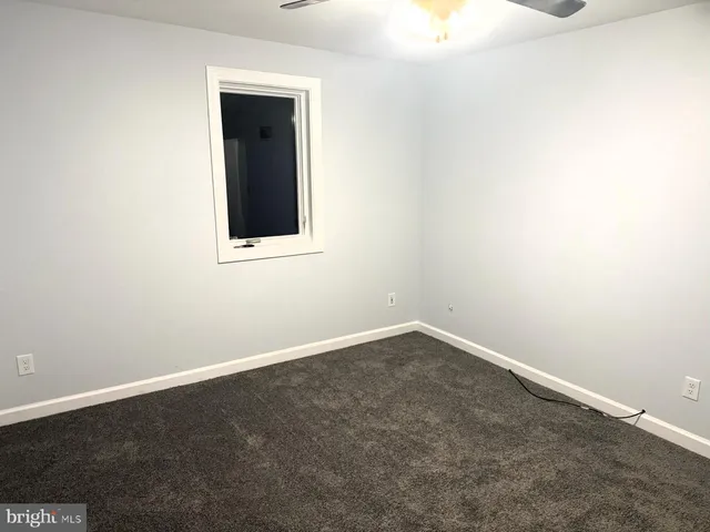 an empty room with a fan & a window