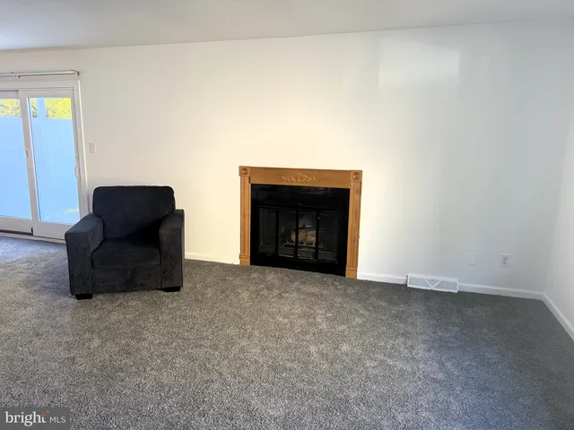 a view of an empty room with window and fire place