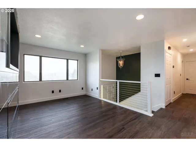 a view of an empty room with wooden floor and windows