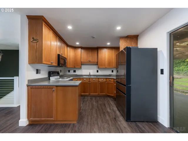 a kitchen with stainless steel appliances granite countertop a refrigerator a sink dishwasher and a stove with wooden floor