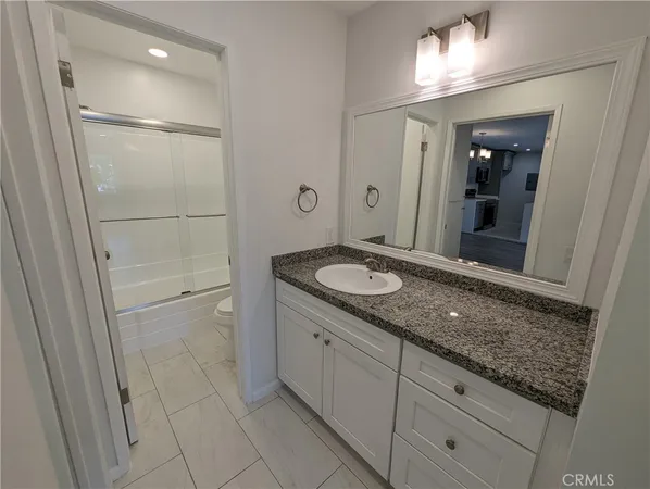a bathroom with a granite countertop sink and a mirror