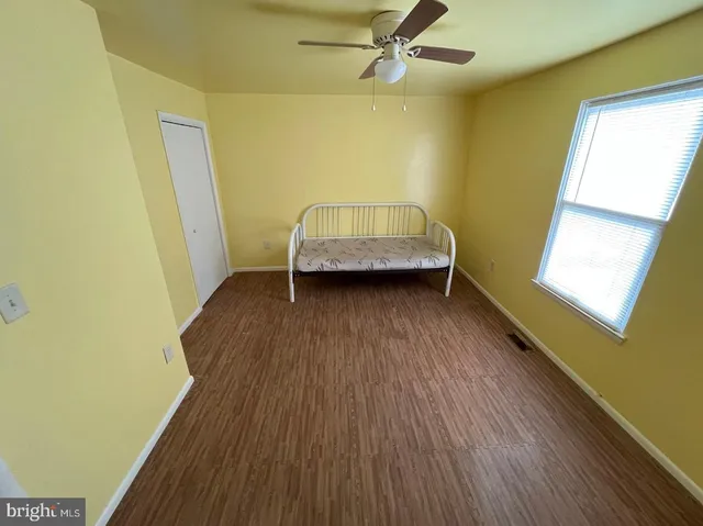 a view of a room with wooden floor and a ceiling fan