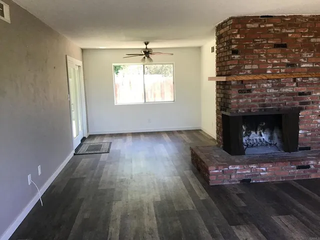 an empty room with wooden floor a fireplace and windows