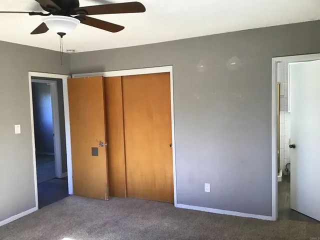 an empty room with closet and a ceiling fan
