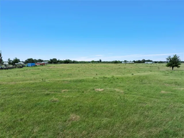 a view of a green field with trees in the background